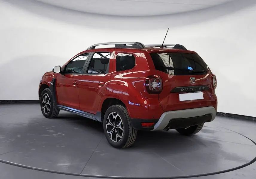 Vue 3/4 arrière droite du Dacia Duster rouge fusion avec jantes alliage noires et toit noir.