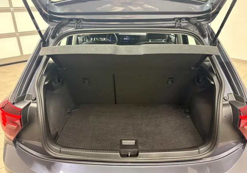 Vue arrière du coffre ouvert d'une Volkswagen Polo gris cendre 2024, montrant l'espace de chargement et la tablette arrière.
