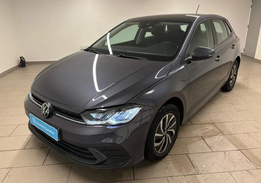 Volkswagen Polo gris cendre 2024 vue 3/4 avant droit avec phares allumés et jantes distinctives.