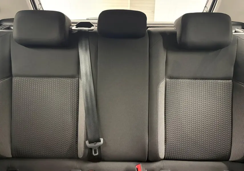 Vue rapprochée des sièges arrière noirs avec appuie-têtes et ceinture de sécurité centrale d'une Volkswagen Polo gris cendre 2024.