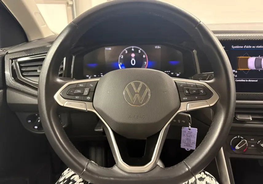 Vue rapprochée du volant noir de la Volkswagen Polo 2024 avec commandes intégrées et tableau de bord numérique allumé.