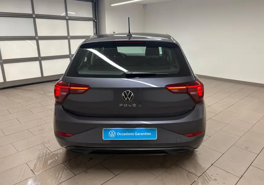 Vue arrière d'une Volkswagen Polo gris cendre 2024, avec feux arrière allumés dans un garage lumineux.