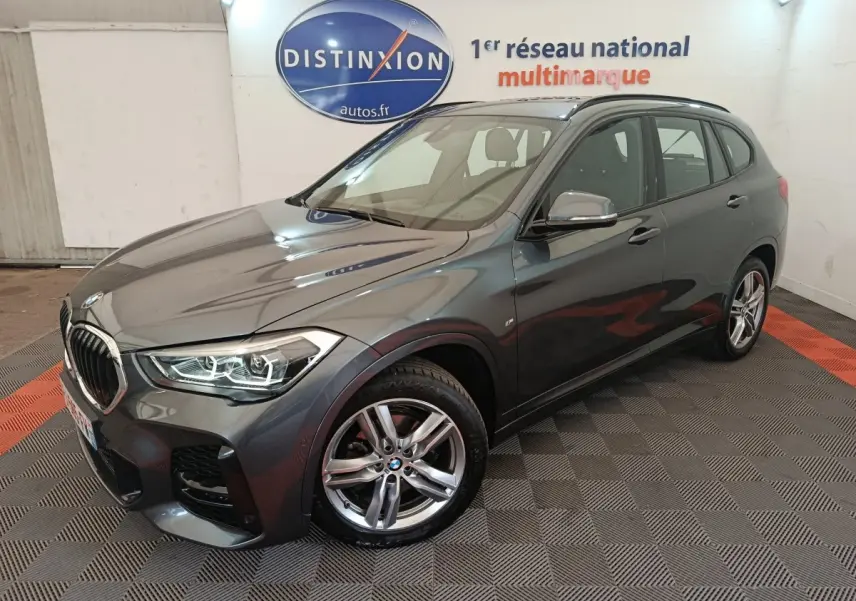 BMW X1 sDrive18i M Sport gris métallisé vue 3/4 avant droit en intérieur showroom avec jantes alliage cinq branches