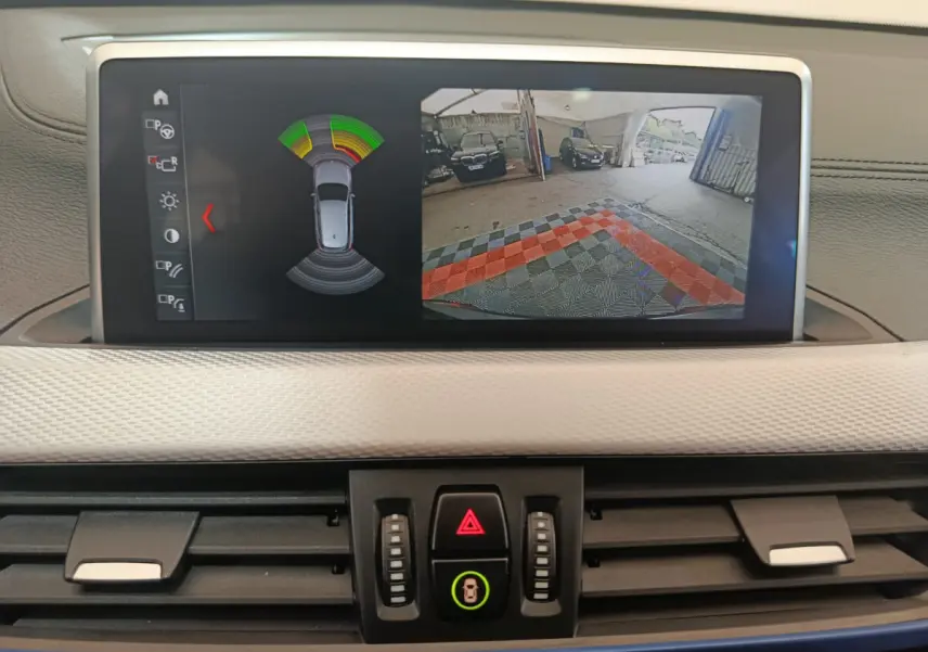 Écran tactile central de la BMW X1 sDrive18i 2019 affichant la caméra de recul et l'aide au stationnement.