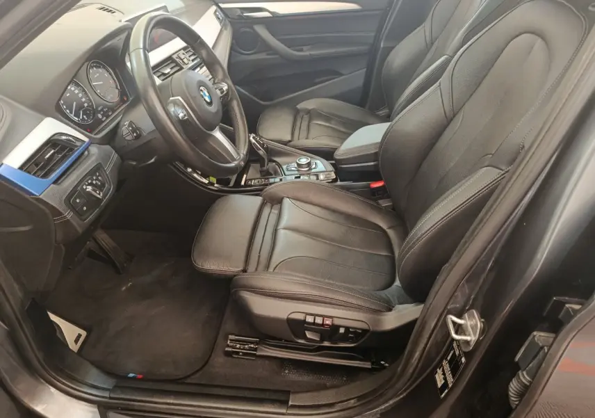 Intérieur avant droit d'une BMW X1 sDrive18i M Sport 2019 avec sièges cuir noirs et tableau de bord moderne.