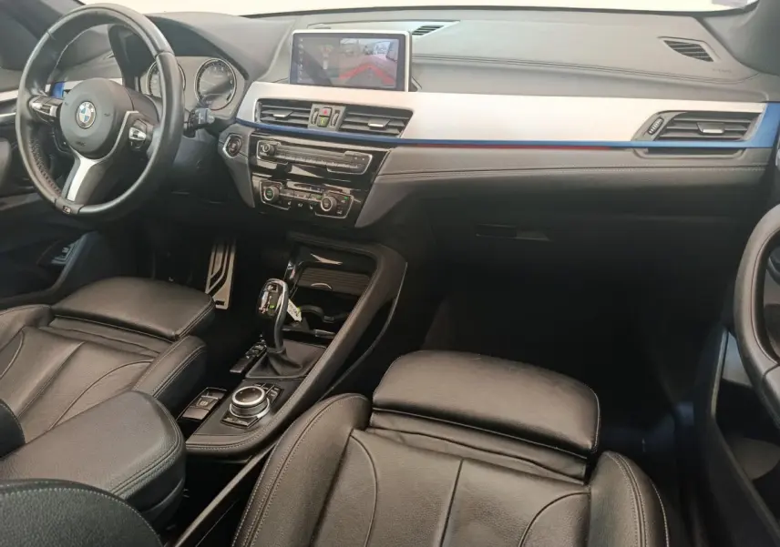 Intérieur noir de BMW X1 sDrive18i M Sport 2019, vue côté conducteur avec tableau de bord et écran tactile central.