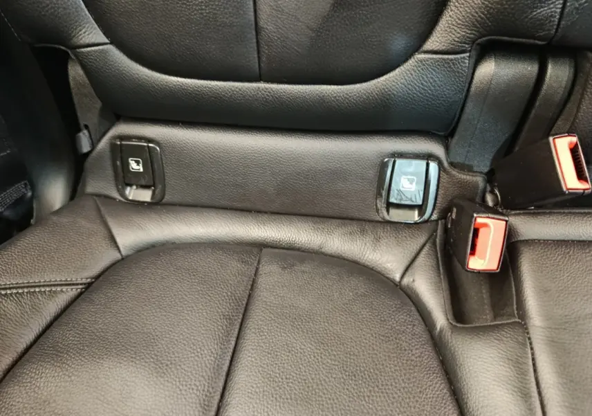 Gros plan sur la banquette arrière noire en cuir du BMW X1 sDrive18i M Sport, avec attaches Isofix et boucles de ceinture rouges.