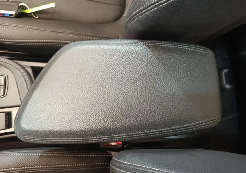 Vue rapprochée de l'accoudoir central en cuir noir du BMW X1 sDrive18i M Sport 2019, avec coutures apparentes.