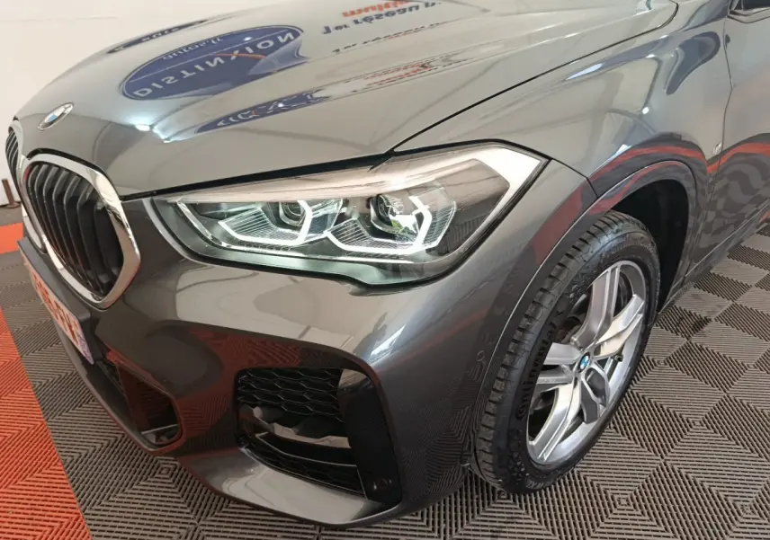 Gros plan sur l'avant droit gris métallisé du BMW X1 sDrive18i M Sport 2019 avec phares LED et jante alliage.
