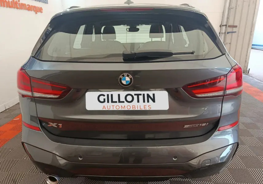 Vue arrière d'un BMW X1 sDrive18i M Sport gris métallisé avec feux LED et logo visible sur le hayon.