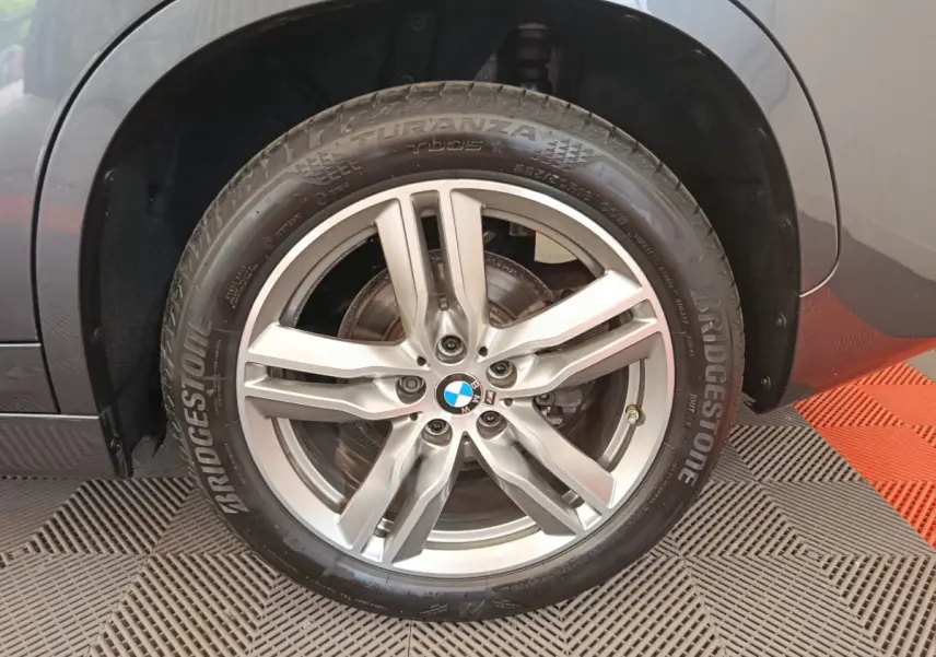 Gros plan sur la roue avant droite grise d'un BMW X1 sDrive18i M Sport avec jante alliage cinq branches.