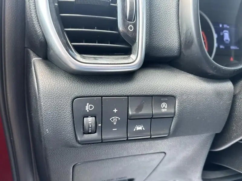 Détail des commandes d'assistance et réglages lumineux côté gauche du tableau de bord du Kia Sportage rouge métal 2021.