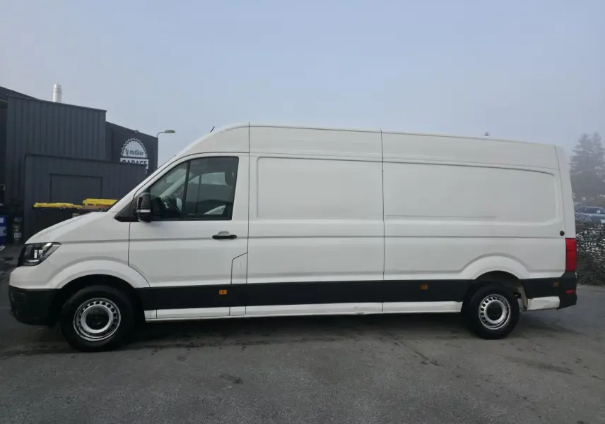 Vue de profil côté gauche d'un Volkswagen Crafter Fourgon blanc avec bas de caisse noir et jantes acier argentées.