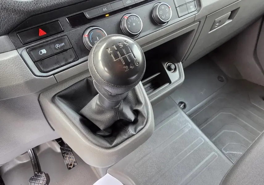 Gros plan sur le levier de vitesses manuel noir et la console centrale grise du Volkswagen Crafter Fourgon 2023.