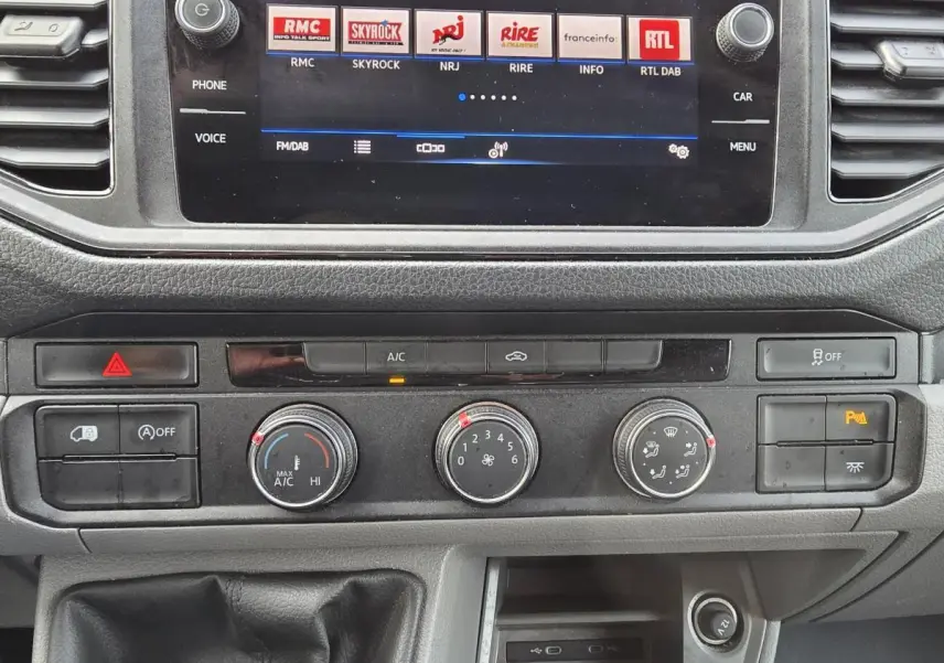 Tableau de bord et console centrale du Volkswagen Crafter blanc 2023, avec écran tactile et commandes climatisation visibles.