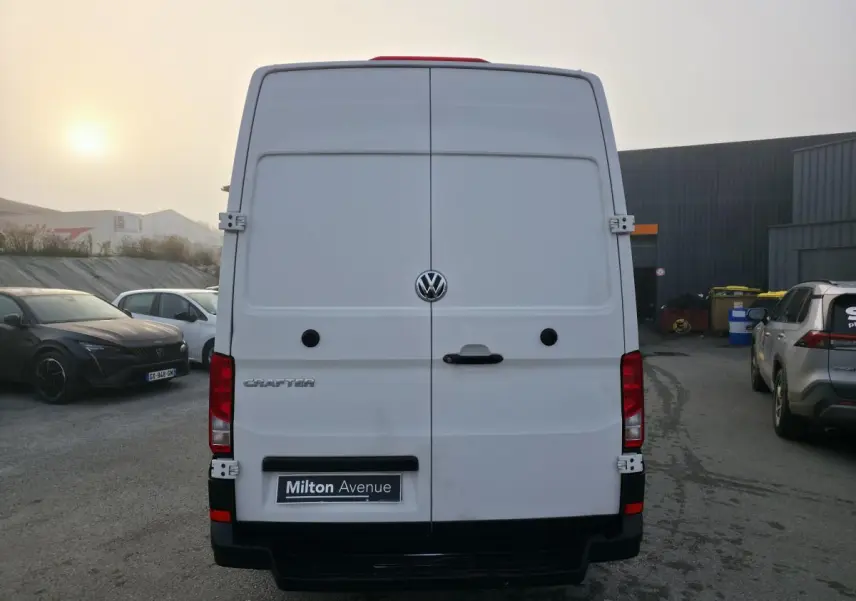 Vue arrière d'un utilitaire Volkswagen Crafter blanc avec portes battantes et logo central visible.