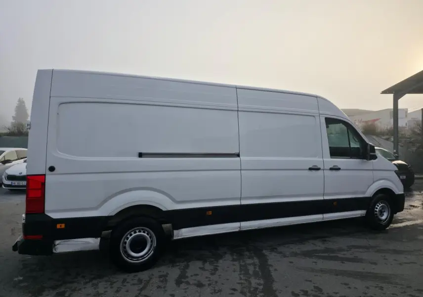 Volkswagen Crafter fourgon blanc vu de profil côté droit avec jantes acier et bande noire basse.