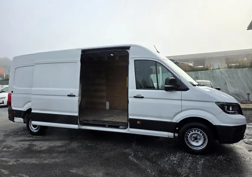 Volkswagen Crafter blanc vue de profil droit avec porte coulissante ouverte montrant l'intérieur en bois.