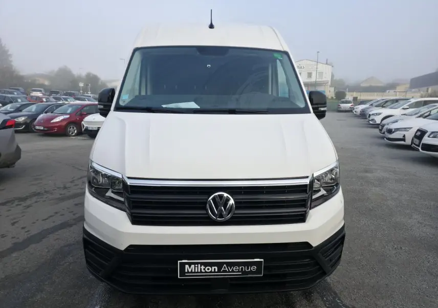Vue avant d'un Volkswagen Crafter fourgon blanc avec calandre noire et plaque Milton Avenue visible.