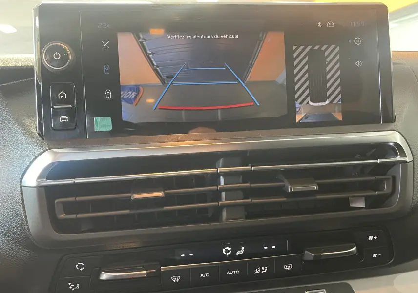 Vue intérieure du tableau de bord du Peugeot Traveller 2026, écran tactile affichant la caméra de recul et commandes de climatisation.