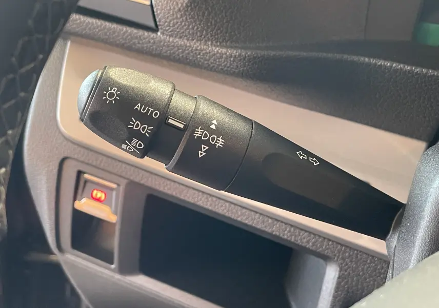 Gros plan sur la commande des feux et clignotants du Peugeot Traveller noir, côté gauche du volant.