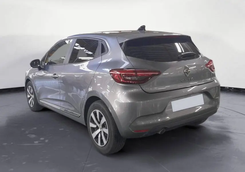 Vue 3/4 arrière gauche d'une Renault Clio gris clair 2023 avec jantes alliage 16 pouces et vitres teintées.
