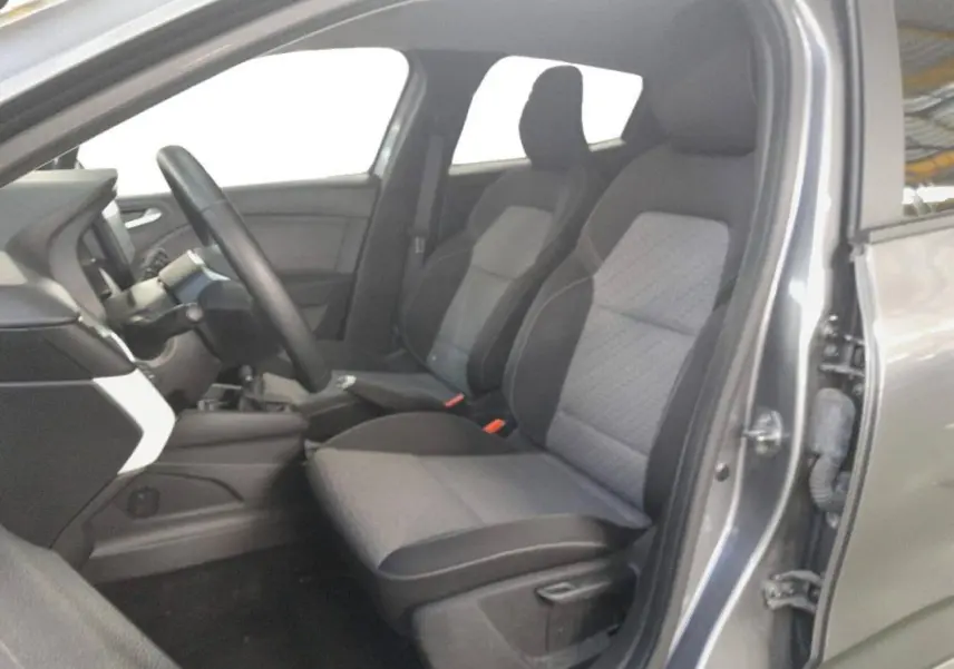 Vue intérieure côté conducteur de la Renault Clio gris clair 2023, sièges tissu bi-tons et tableau de bord moderne.