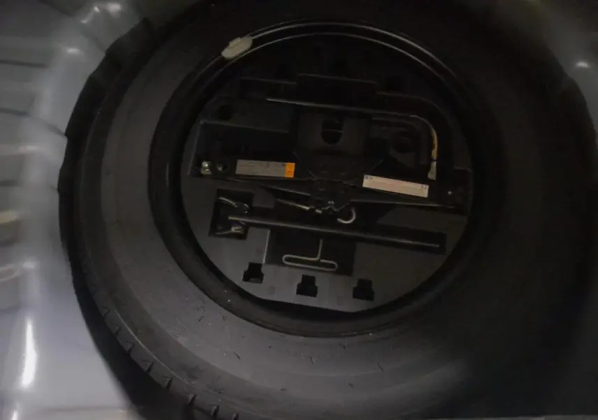 Gros plan sur la roue de secours noire dans le coffre d'une Renault Clio gris clair V TCe 90 Evolution 2023.
