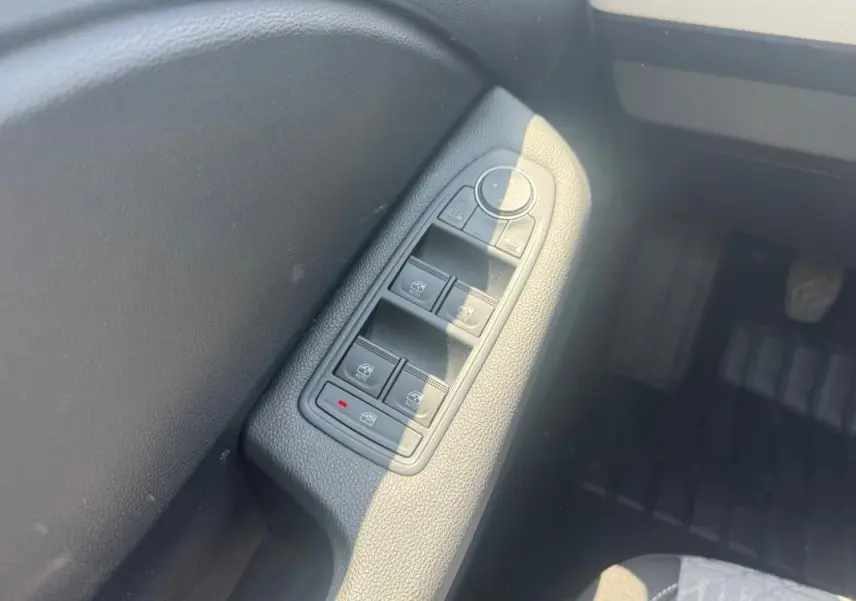 Gros plan sur les commandes des vitres électriques côté conducteur de la Renault Clio gris clair 2023.