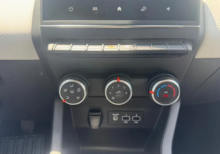 Vue rapprochée du tableau de bord de la Renault Clio V TCe 90 Evolution 2023, montrant les commandes de climatisation et ports USB.