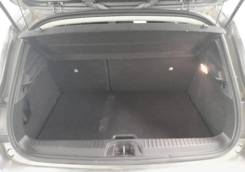 Coffre ouvert vu de l'arrière d'une Renault Clio gris clair 2023, montrant l'espace de chargement vide.
