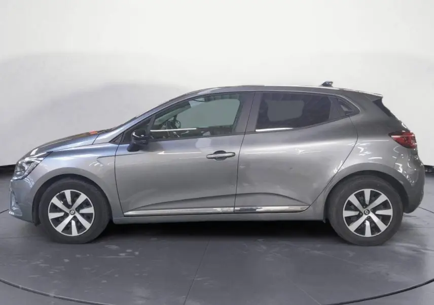 Profil côté gauche d'une Renault Clio 2023 gris clair avec jantes alliage 16 pouces et roue de secours visible.