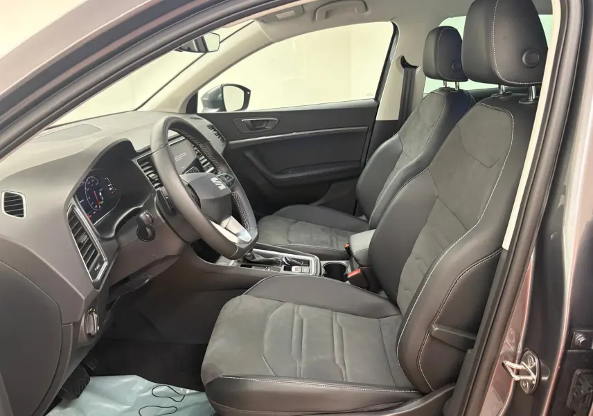 Vue intérieure côté conducteur du SEAT Ateca 2025 avec sièges en cuir et alcantara gris, tableau de bord moderne.