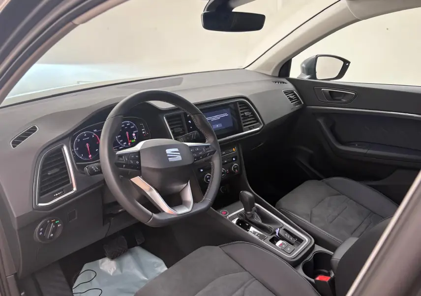 Vue intérieure côté conducteur du SEAT Ateca 2025 avec tableau de bord noir et volant multifonction.