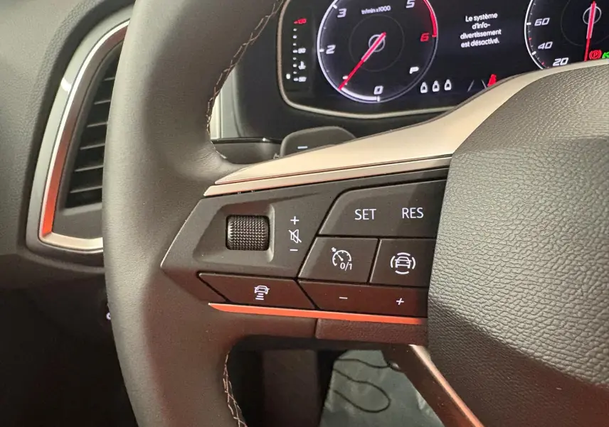 Gros plan sur le volant du SEAT Ateca 2025, montrant les commandes de régulateur et l'affichage du tableau de bord numérique.