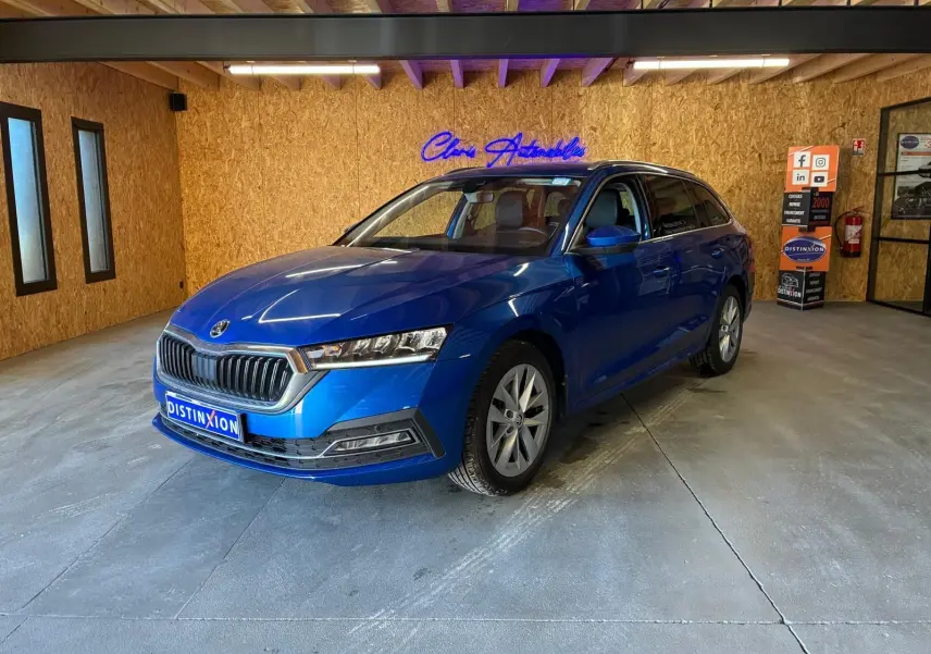 SKODA OCTAVIA COMBI 2024 bleu en 3/4 avant droit, avec calandre chromée et phares LED dans un showroom.