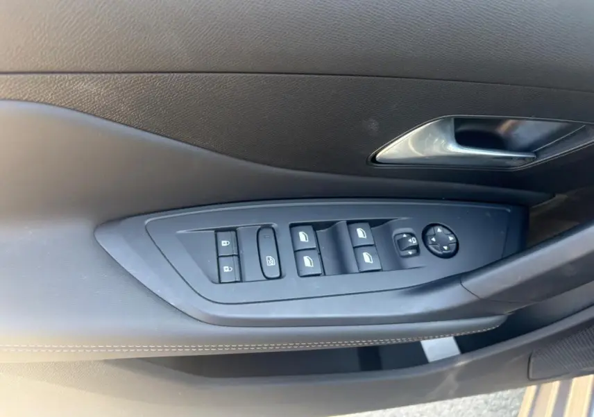 Gros plan sur la commande des vitres et rétroviseurs côté gauche de la porte intérieure d’une Peugeot 308 PHEV 180 e-EAT8 Allure gris clair 2024.