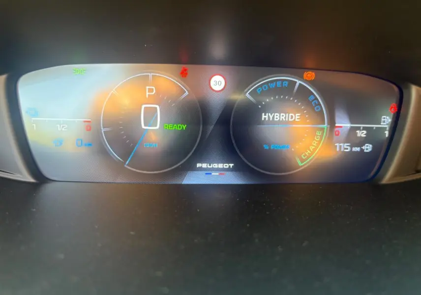 Tableau de bord numérique du Peugeot 308 PHEV 2024 affichant mode hybride, vitesse à zéro et autonomie électrique de 115 km.