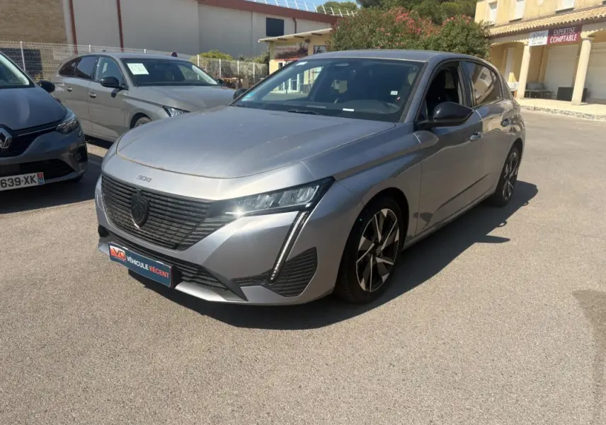 Peugeot 308 PHEV 180 e-EAT8 Allure gris clair vue 3/4 avant avec calandre noire et jantes alliage distinctives.