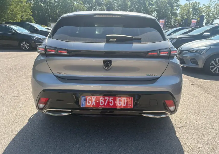 Vue arrière d’une Peugeot 308 PHEV 180 e-EAT8 Allure gris clair 2024 avec feux LED et double sortie d’échappement intégrée.