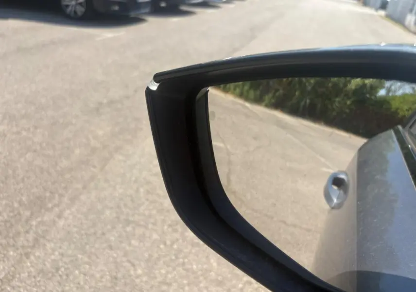 Rétroviseur côté droit d'une Peugeot 308 PHEV 180 e-EAT8 Allure gris clair 2024, avec poignée de porte visible.
