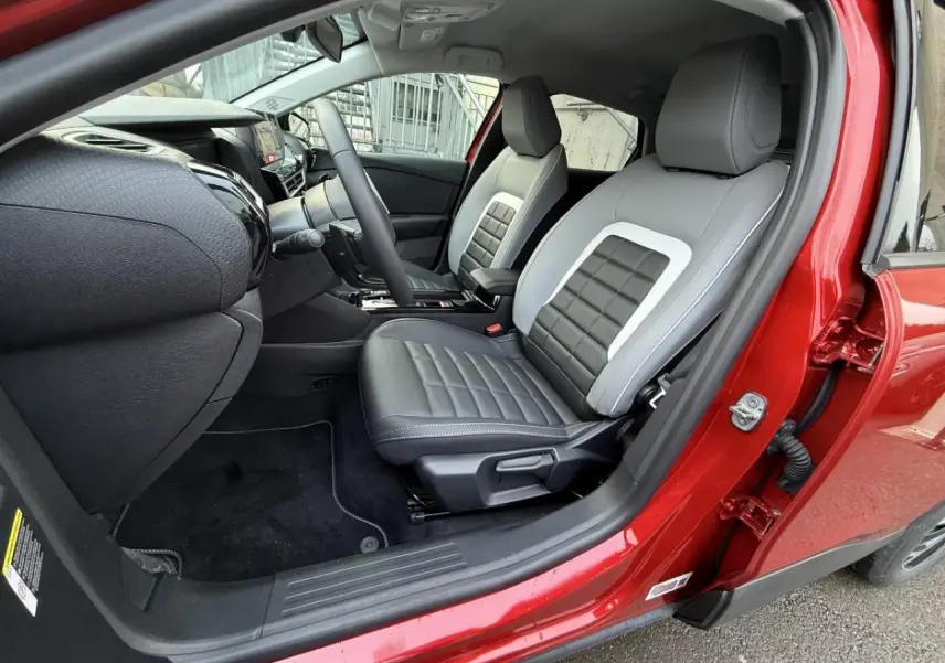 Intérieur du Citroën C4 2025 rouge elixir, vue côté conducteur ouverte, sièges bicolores gris et noir avec surpiqûres.