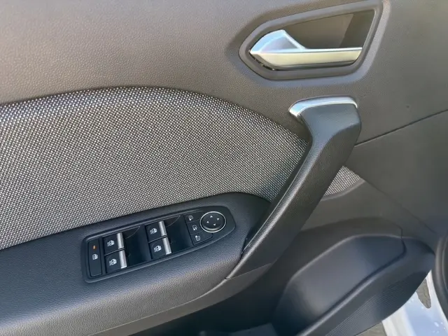 Gros plan sur la porte intérieure côté conducteur de la Renault Symbioz gris clair, avec commandes de vitres et poignée noire.