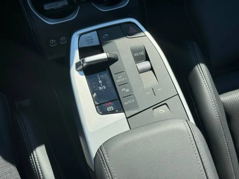 Gros plan sur la console centrale grise et les commandes de la boîte automatique dans l'habitacle noir d'une BMW X2 2025.