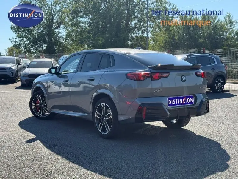 BMW X2 sDrive20dA 2025 gris Skyscraper métallisé, vue 3/4 arrière droit avec jantes alu et spoiler noir.