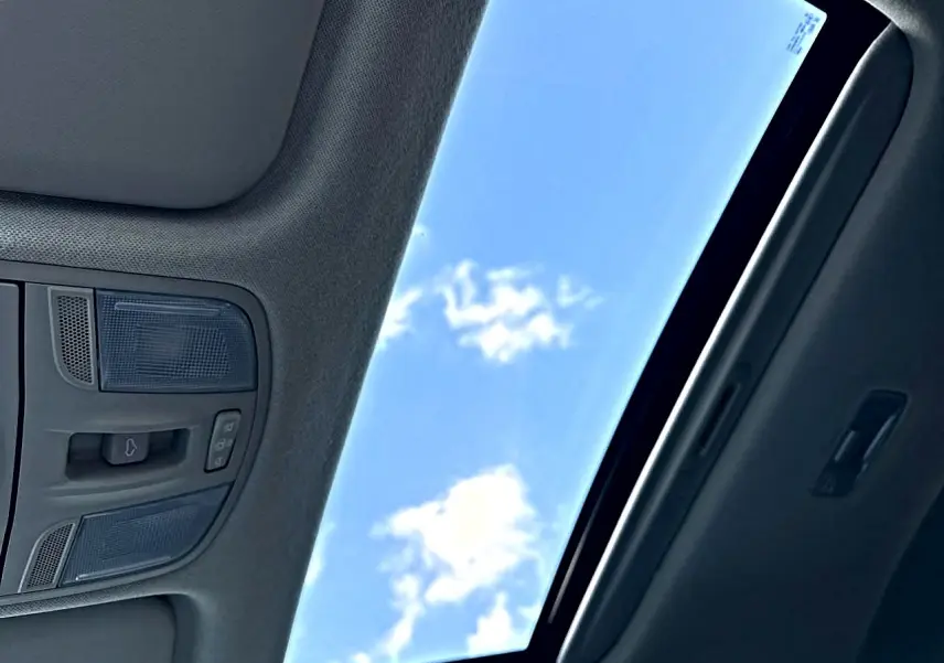 Toit ouvrant panoramique ouvert avec ciel bleu visible, intérieur gris foncé du Kia Stonic 2025 GT Line.