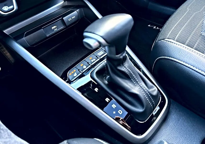 Gros plan sur le levier de vitesses automatique noir et cuir, entouré de commandes et console grise du Kia Stonic gris.