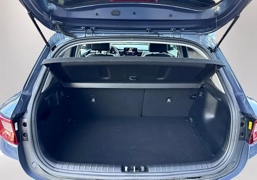Coffre ouvert en vue arrière d'un KIA STONIC gris 2025, montrant l'espace de chargement et l'intérieur du véhicule.