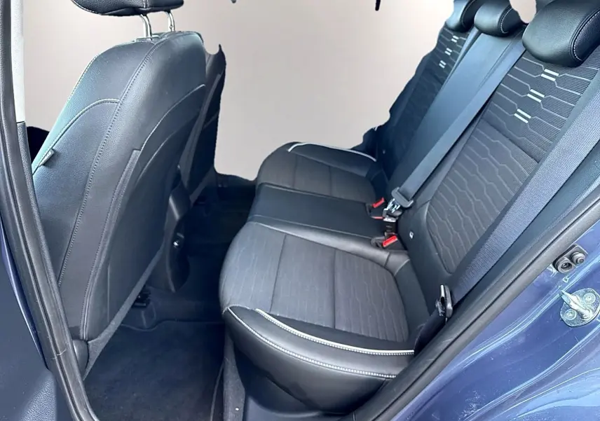 Vue côté droit des sièges arrière noirs en tissu et cuir du Kia Stonic 2025 avec ceinture de sécurité et porte ouverte.