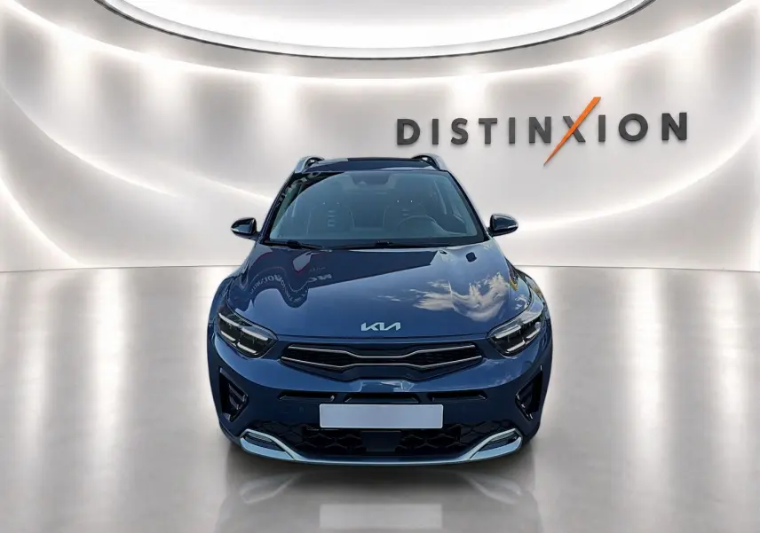 Vue avant d'un KIA Stonic gris métallisé avec calandre noire et logo KIA sur capot, dans un studio lumineux.